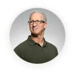 Professional headshot of a smiling middle-aged man wearing glasses and a dark green polo shirt.